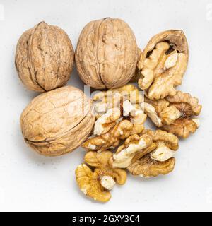 several peeled and whole walnuts close up on gray ceramic plate Stock Photo