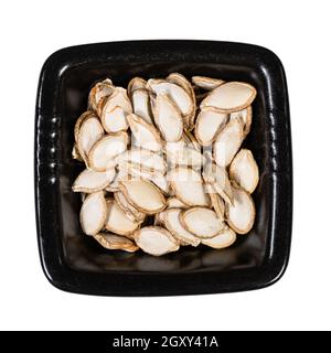 top view of whole pumpkin seeds in black bowl isolated on white background Stock Photo