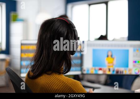 Creative photographer editor retouching photos of a client on performance PC with two displays setup. Woman retoucher working in editing software app sitting office holding stylus pen Stock Photo