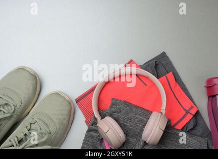 pair of green sneakers, wireless headphones on a gray background. Things and gadgets for sports, running, flat lay Stock Photo