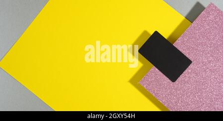 blank black rectangular business card on a creative background from sheets of paper with shadow, gray background and yellow sheets, flat lay Stock Photo