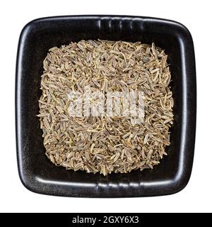 top view of kala zeera (Elwendia persica) seeds in black bowl isolated on white background Stock Photo