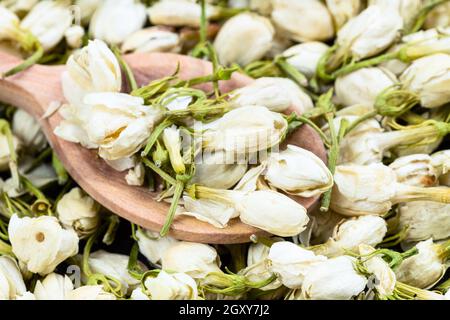 wooden spoon with dried jasmine flowers close up on pile of dried flowers Stock Photo