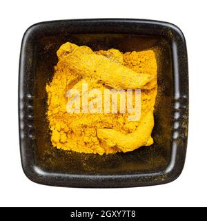 top view of Turmeric (Curcuma) powder and roots in black bowl isolated on white background Stock Photo