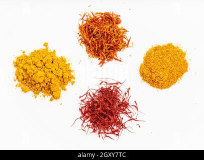 top view of saffron and natural substitutes (crocus threads, turmeric powder, safflower petals, ground tagetes) on white plate Stock Photo