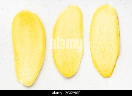 top view of slices of fresh ginger root on gray plate close up Stock Photo