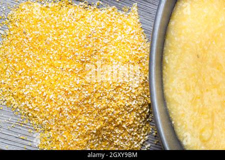 top view of pile of cornmeal and cooked maize porridge in gray bowl on gray wooden table Stock Photo