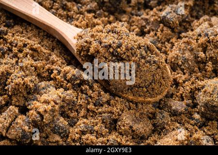 wooden spoon with dark muscovado cane sugar close up on pile of sugar Stock Photo