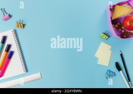 Primary school flat lay concept with assorted school supplies, notepad, pen, pencil, markets, stickers, paper clips and lunch box with sandwich, nuts Stock Photo