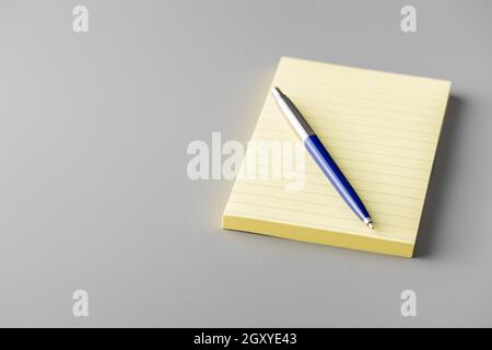 Blank sticky paper notepad and pen on a gray table. Stock Photo