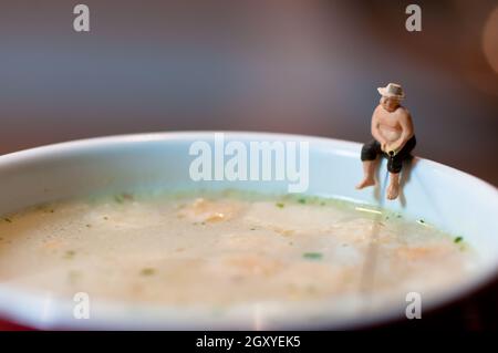 Tiny fisherman fishing in a soup mug.. Macro photo Stock Photo