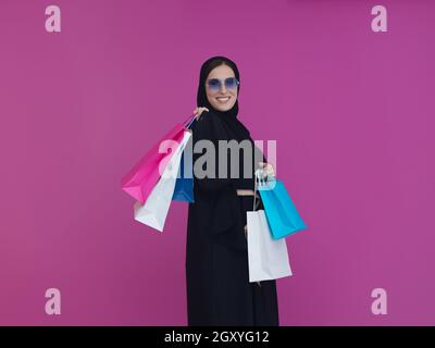 Happy muslim girl posing with shopping bags. Arabic woman wearing traditional black clothes and sunglasses representing rich and luxurious lifestyle Stock Photo