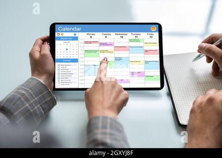 Close-up Of Businessperson Looking At Calendar On Digital Tablet Stock Photo