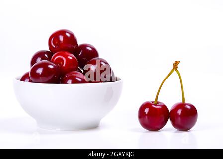 Cherry berries in a white cup on a white background. Isolated. Ripe cherries. Red delicious cherry. Place for advertising, lettering, logo, text, layo Stock Photo