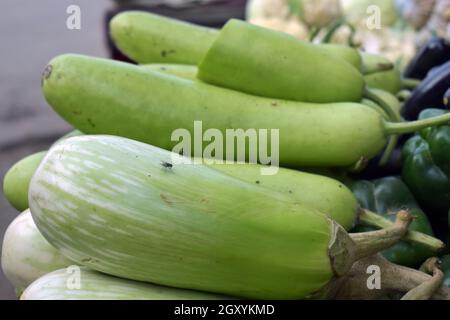 A closeup shot of a green eggplant and bottle gourd in a market place Stock Photo