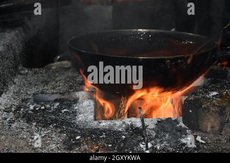 Old cooking pot stove using firewood.Large metal cauldron over a fire in a farm house used for boiling water. Stock Photo