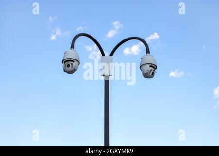 Surveillance cctv (closed circuit television) camera installed in public park on blue sky background for protection against crime, observation of peop Stock Photo