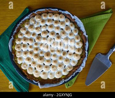 Lemon Pie with merengue on two green napkins decorated with a cake spatula server. Top View Stock Photo