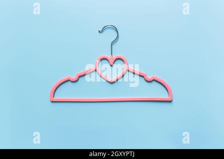 Black Friday or clothing industry concept on blue background flat lay with single one pink clothes hanger with heart shape on hanger Stock Photo