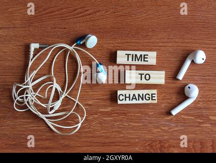 Top view of two types of earphones and wooden cube with text TIME TO CHANGE Stock Photo