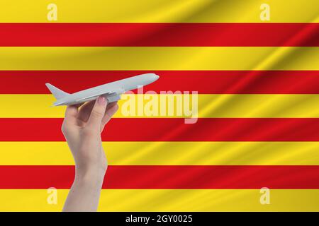 Airplane in hand with national flag of Catalonia. Travel to Catalonia. Stock Photo