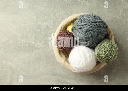 Multi colored balls of yarn in a wicker basket on a light gray background. Stock Photo