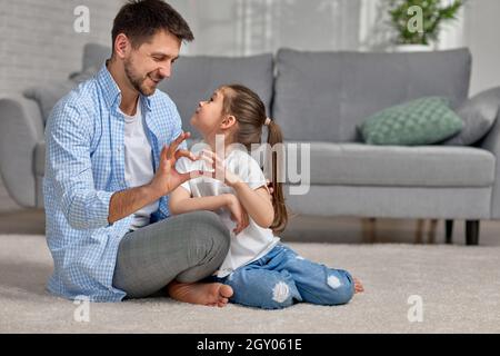 handsome father and cute little child daughter showing love sign. dad and girl kid make hand heart gesture. Happy Father's day. Stock Photo