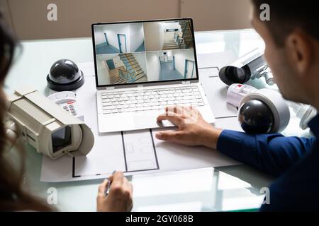 Person Watching Footage On Digital Tablet With Security Equipment On Blueprint Stock Photo