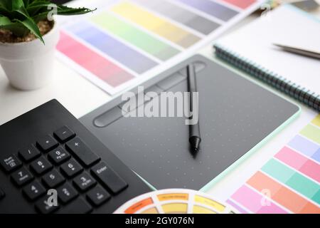 Graphic tablet with stylus and color palette on table Stock Photo