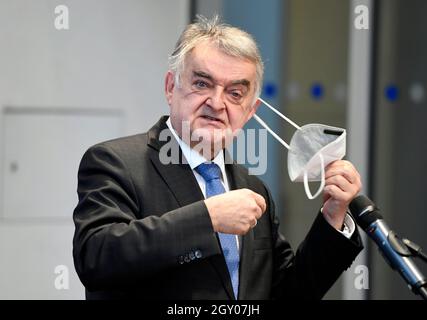 Duesseldorf, Germany. 06th Oct, 2021. Herbert Reul (CDU), Minister of the Interior of North Rhine-Westphalia, takes off his mask as he comes to tell the press about the state-wide police operation against money laundering and terrorist financing. Credit: Roberto Pfeil/dpa/Alamy Live News Stock Photo