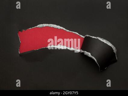 Black torn paper on red background. Black Friday campaign. Stock Photo