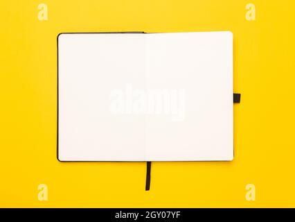 Black notebook opened isolated on yellow background. Stock Photo