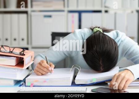 Tired woman lies on folder with working documents in office Stock Photo