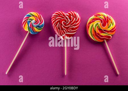 Set of three lollipops with rainbow colour and fruit flawor with purple background. Stock Photo