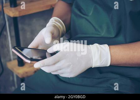 Two Doctor in green surgical gown hand working with smart phone. Medical technology network team meeting concept. Stock Photo