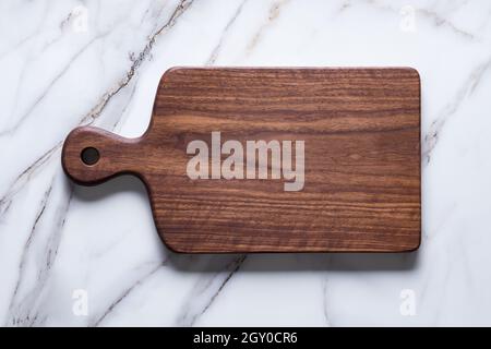 Handmade black walnut chopping board on stone table. Stock Photo