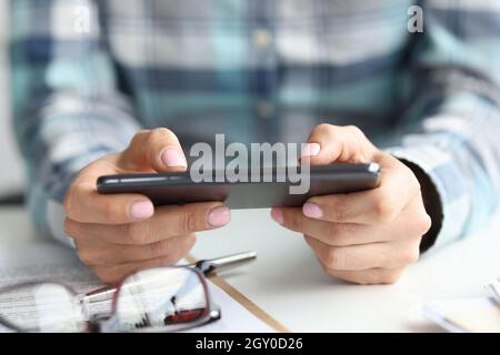 Black smartphone in female hands at workplace Stock Photo