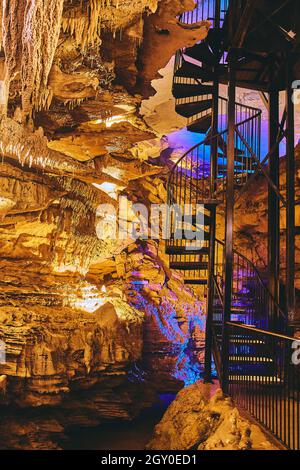 Spiral Staircase in underground cave with orange and blue lights Stock Photo