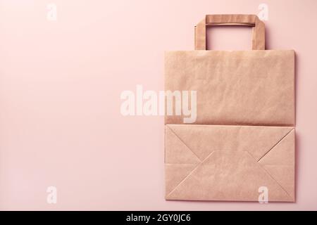 Paper bag, cups, dishes, wooden forks, drinking straws, fast food containers, wooden cutlery on pink background. Eco craft paper tableware. Recycling Stock Photo