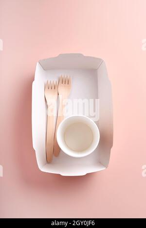 Paper cups, dishes, bag, wooden forks, drinking straws, fast food containers, wooden cutlery on pink background. Eco craft paper tableware. Recycling Stock Photo