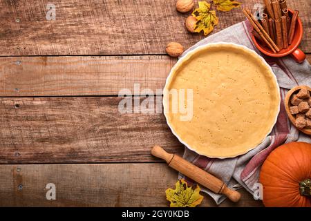 Dough for baking quiche, tart or pie in ceramic baking form ready for bake on kitchen towel over old rustic plank wooden background. Top view, copy sp Stock Photo