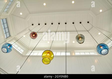 Multicolored glass globes with light bulbs inside hang from a skylight Stock Photo