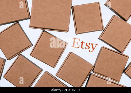 Etsy logo on a white background surrounded by parcel boxes. Stock Photo