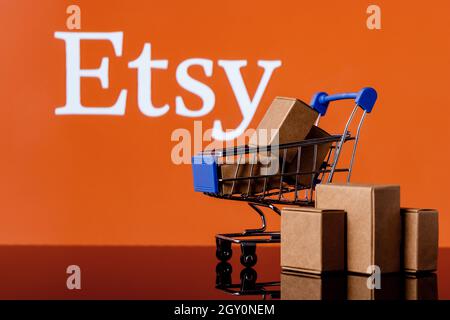 Shopping cart with parcels on the background of the Etsy logo. Stock Photo