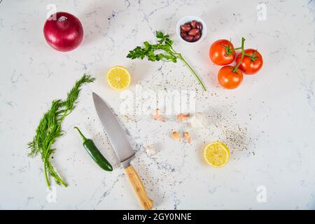 Fresh produce ingredients, spices, and knife on white marble Stock Photo