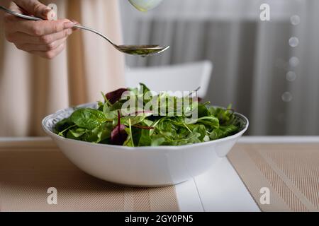 healthy tasty winter salad, mixture of spinach, arugula and lettuce leaves on a plate on the table. Stock Photo