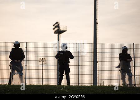 Silhouettes of policemen standing next to the football field (inscription in Polish Police) Stock Photo