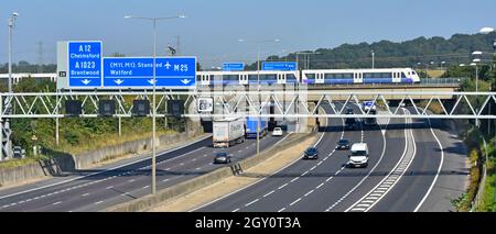 M25 motorway gantry road sign junction 28 Brentwood Essex Elizabeth line new Crossrail passenger commuter train to London on railway bridge England UK Stock Photo