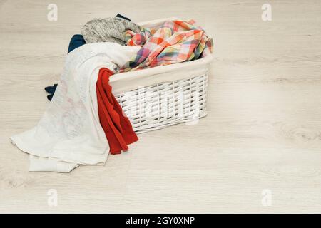 dirty laundry for washing in a wicker white basket Stock Photo