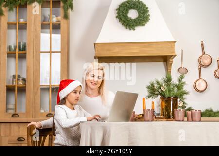 Asian mother and daughter using laptop Video Call Facetime Chatting Communication to father with decorating Christmas tree in white room at home Stock Photo